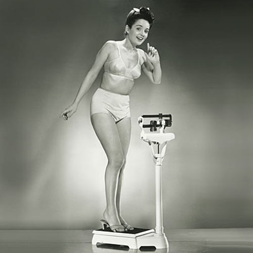 Woman standing on weighing scales, portrait