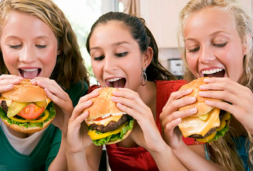 Adolescentes comiendo hamburguesas
