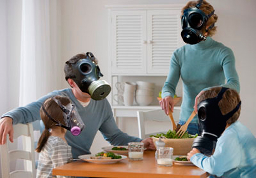 Foto de una familia sentada a la mesa con máscaras antigas