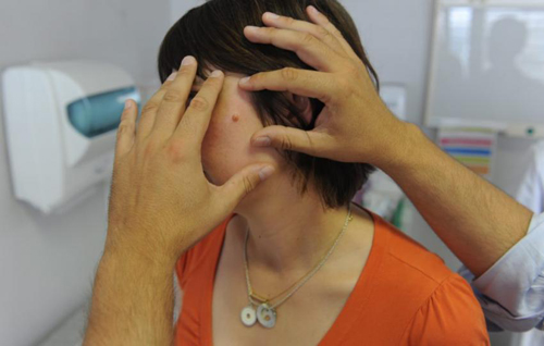 Un dermatólogo examina una mancha en el rostro Piel500 baja