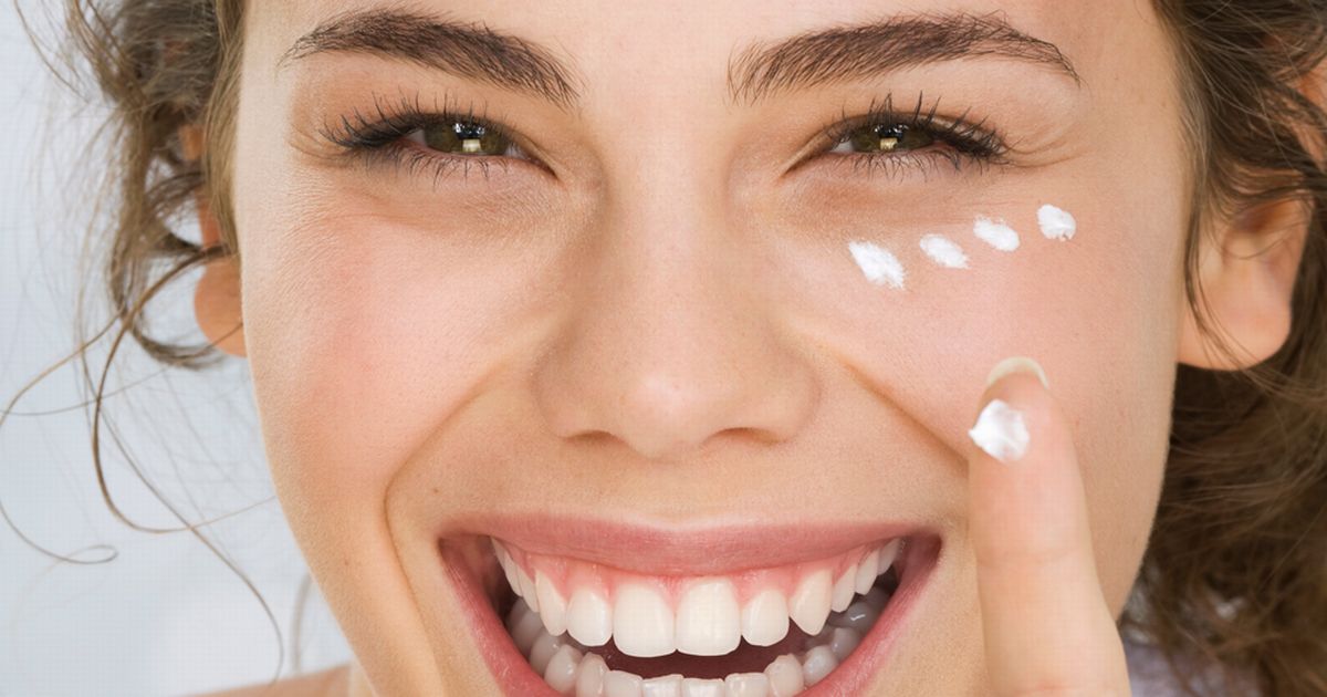 Young Woman Putting Cream On Face Smiling