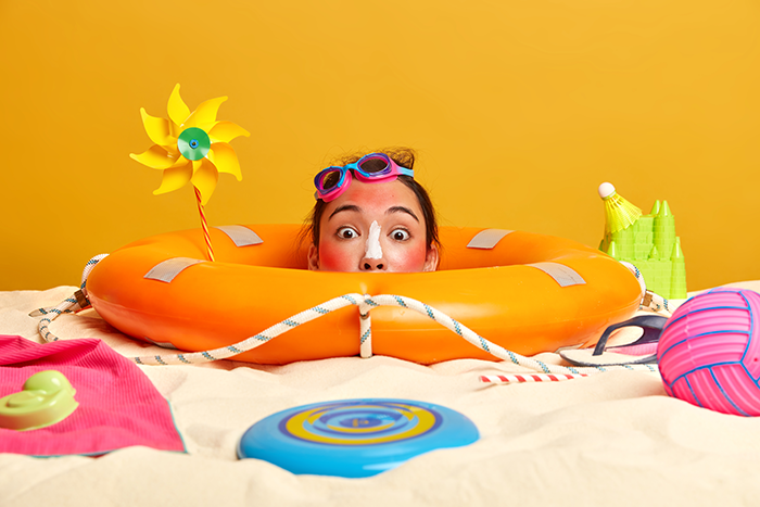 Young Woman Head With Sunscreen Cream On Face Surrounded By Beach Accessories