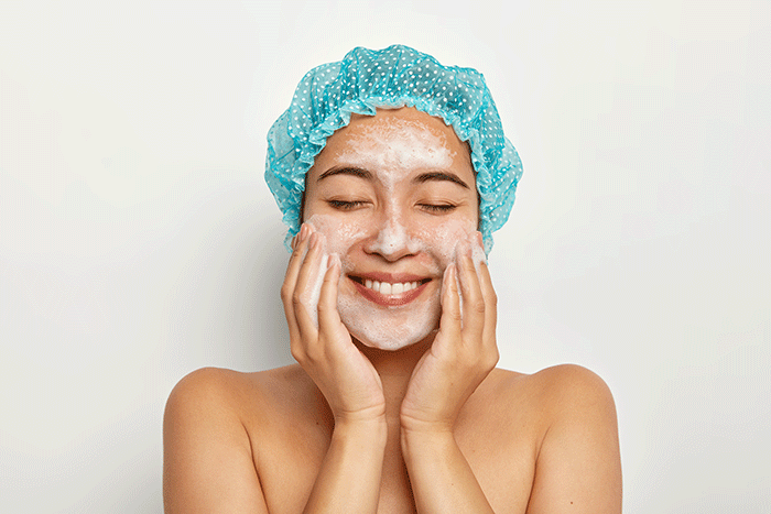 Portrait Of Delighted Young Female Model Applies Foaming Facial Cleanser Touches Cheeks Has Perfect Fresh Clean Skin After Shower Cleans Pores