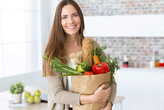 Beautiful Young Woman With Vegetables In Grocery Bag At Home